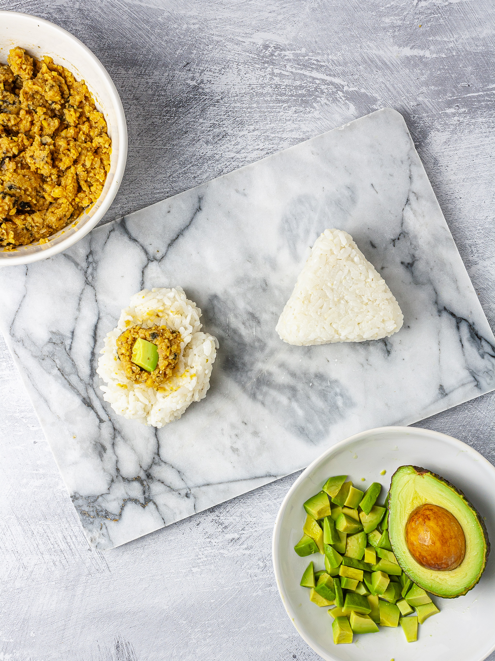 Filling the onigiri with vegan tuna and avocado and then shaping them into triangles.