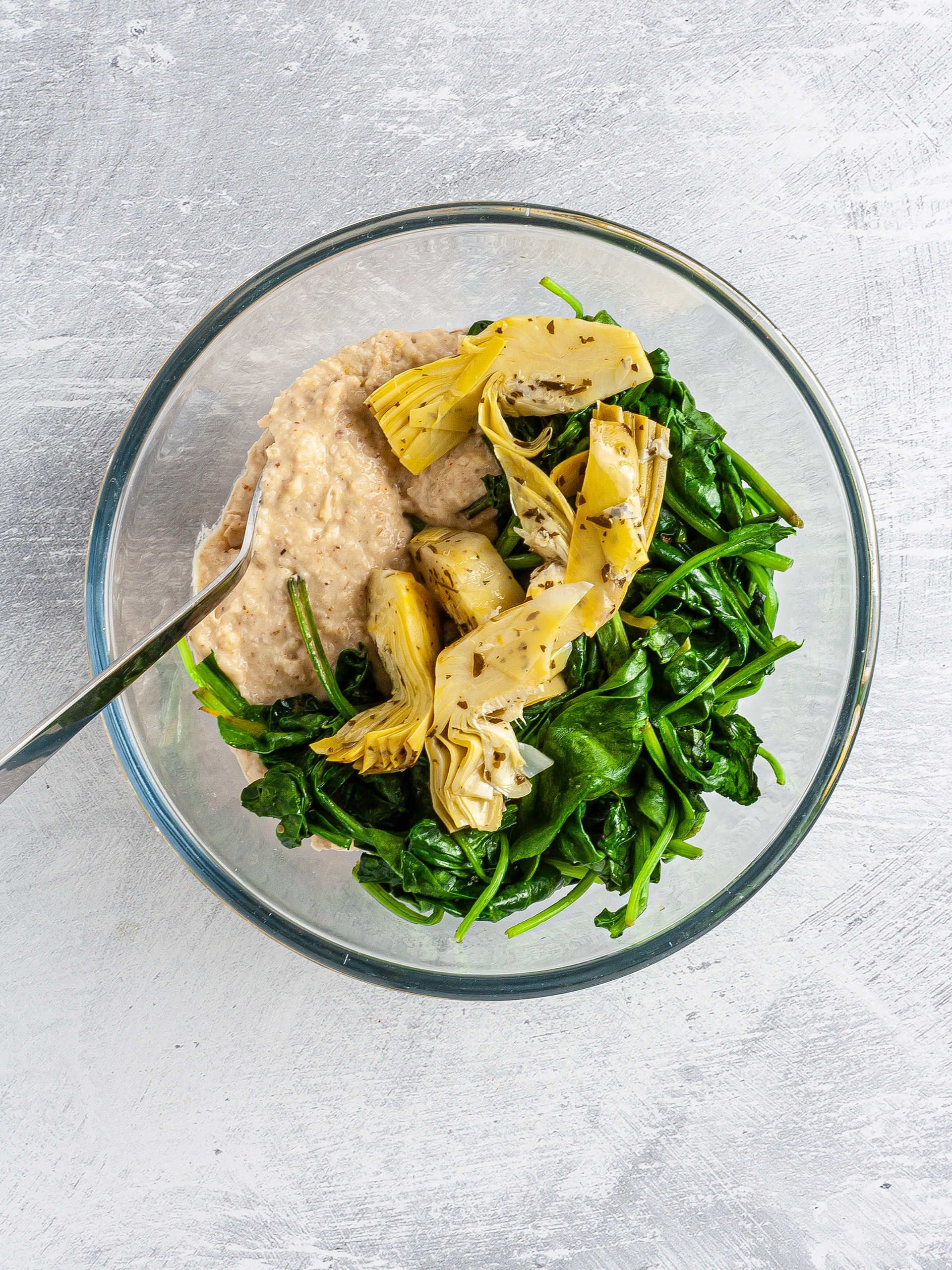 Bean dip mixed with artichoke hearts and cooked spinach