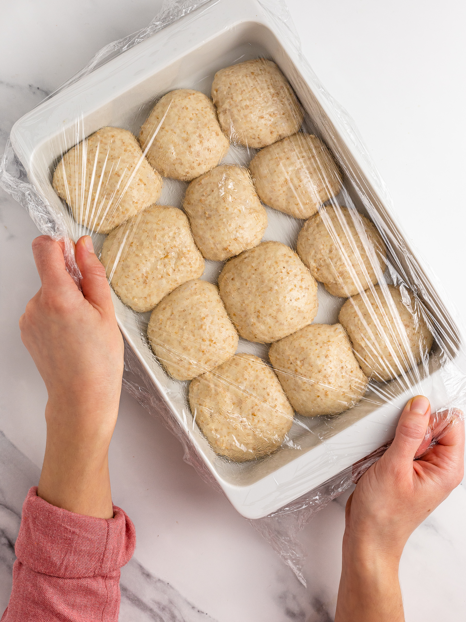 Hawaiian rolls proving in a tray covered with cling film