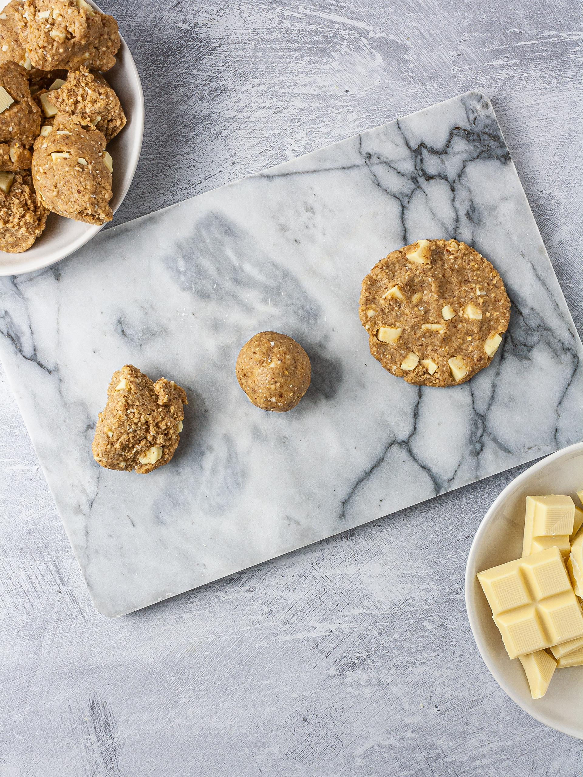 Vegan white chocolate cookie dough shaped as ball and then flattened as a cookie.