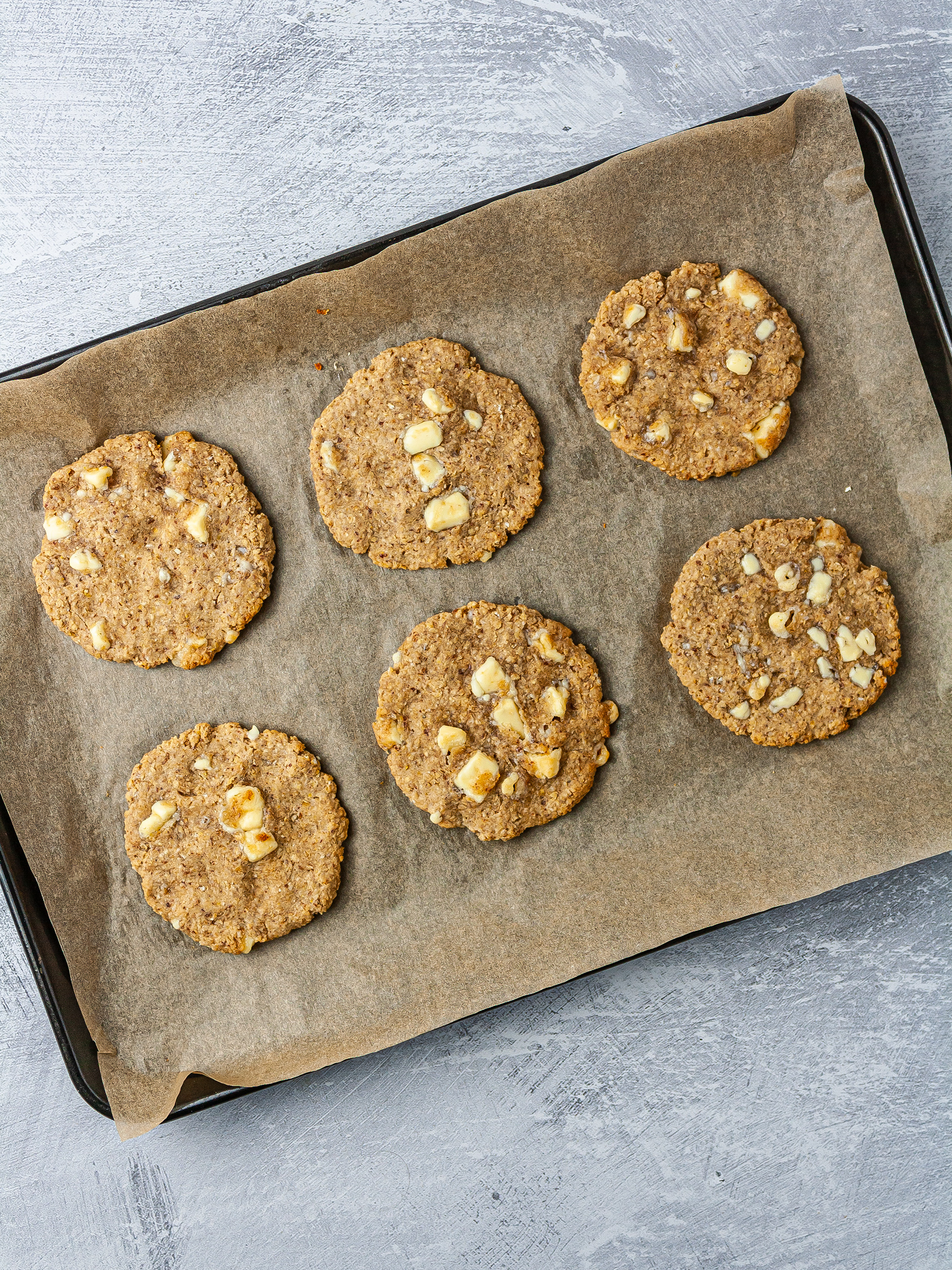 Vegan white chocolate chip cookies baked on a baking tray.