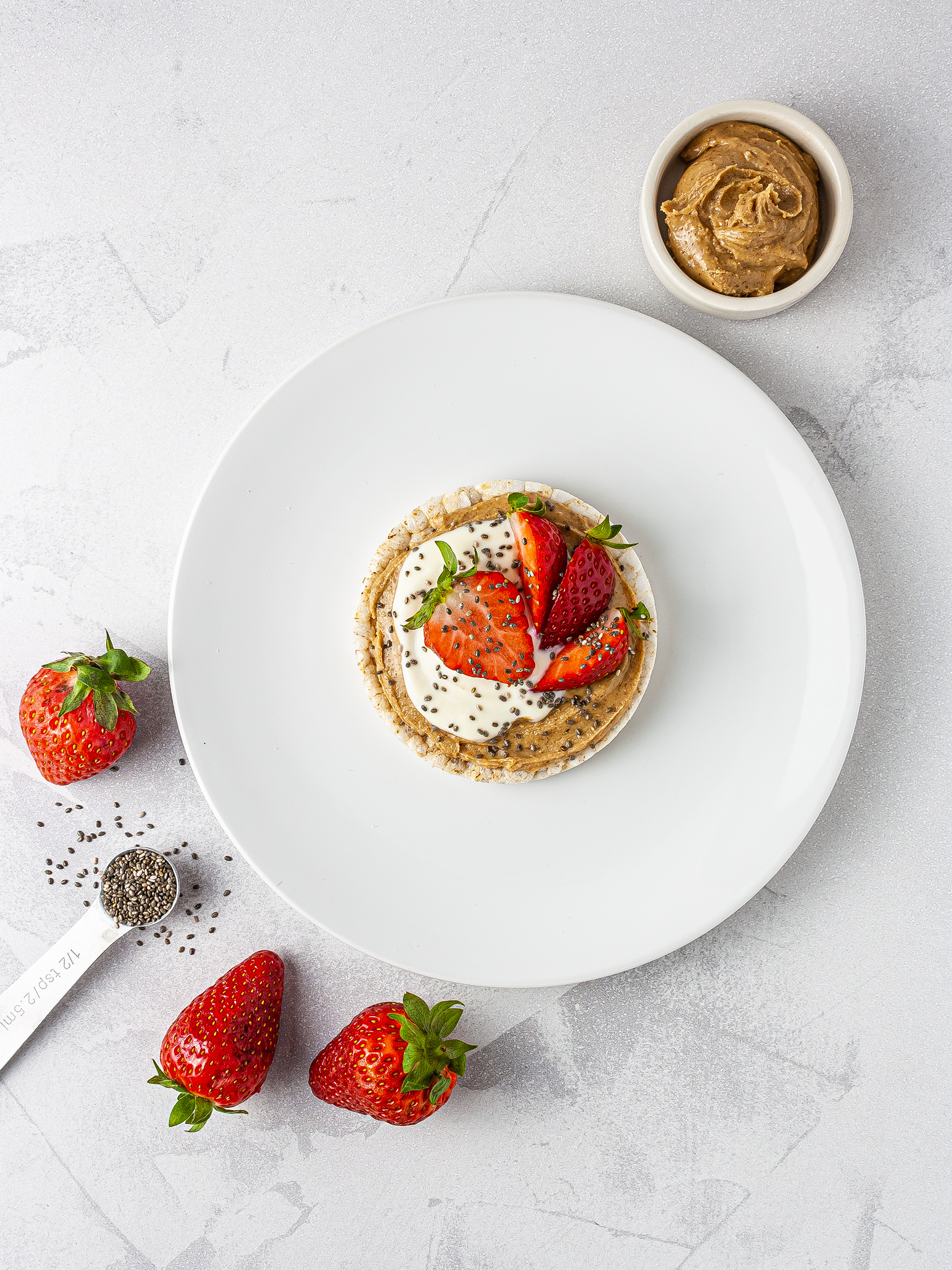 Rice cake with almond butter, yogurt, strawberries and chia seeds.