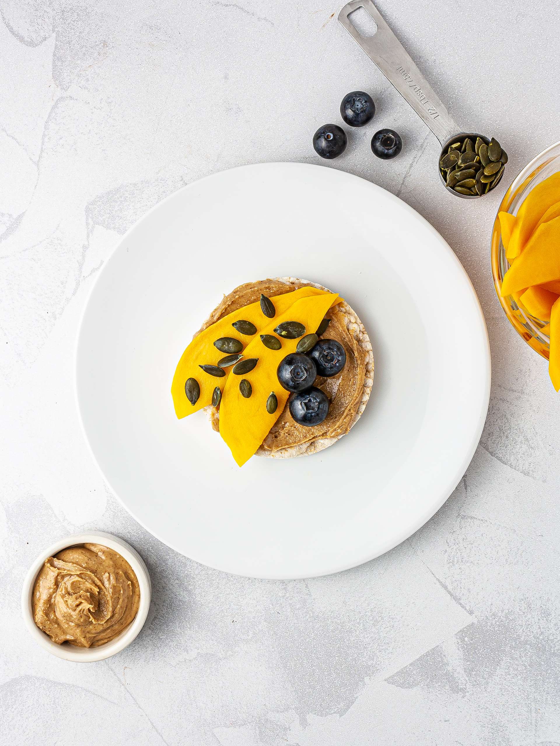 Rice cake with mango, blueberries and pumpkin seeds.
