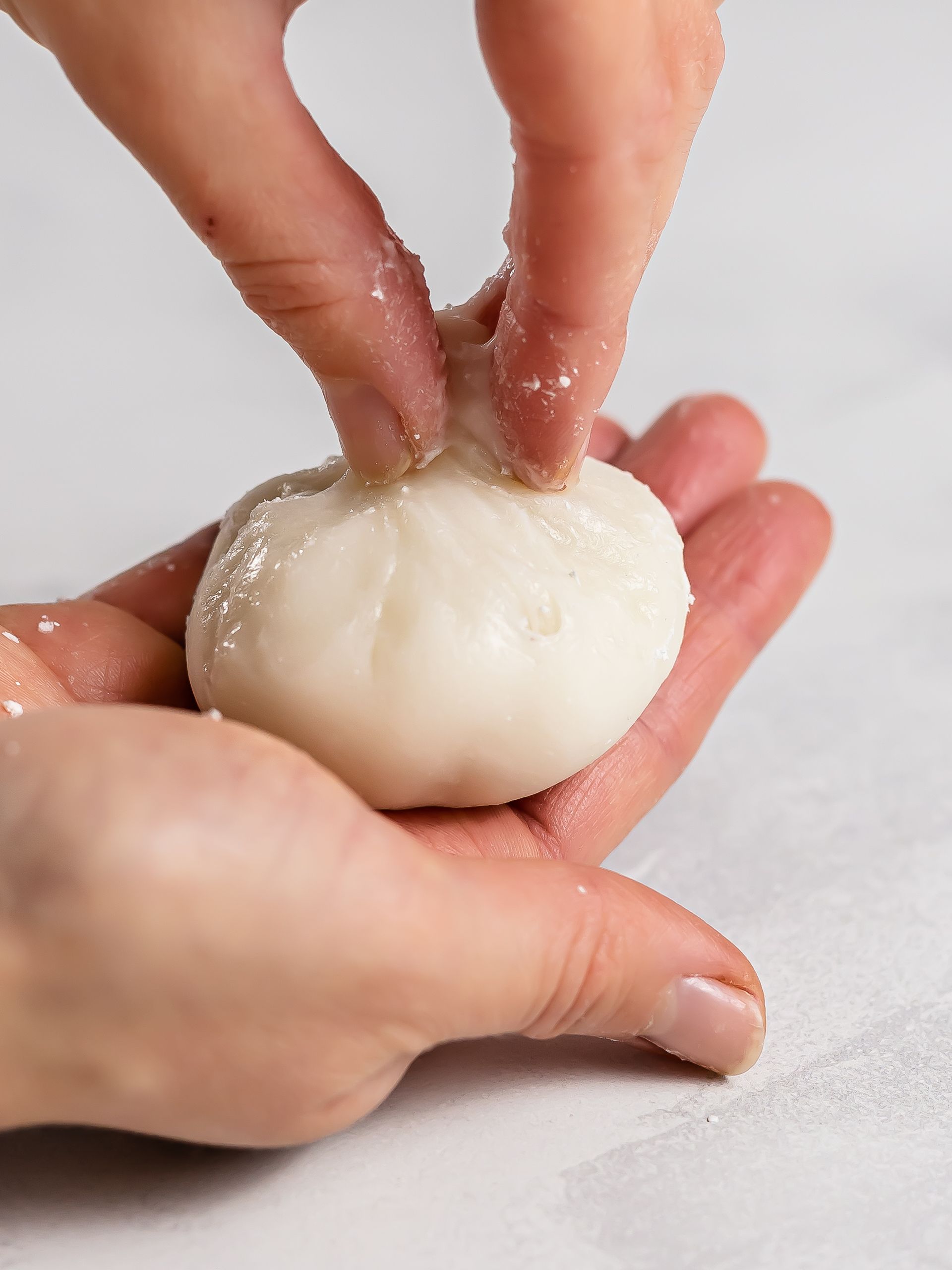 woman twisting and pinching a mochi dough ball in her hands