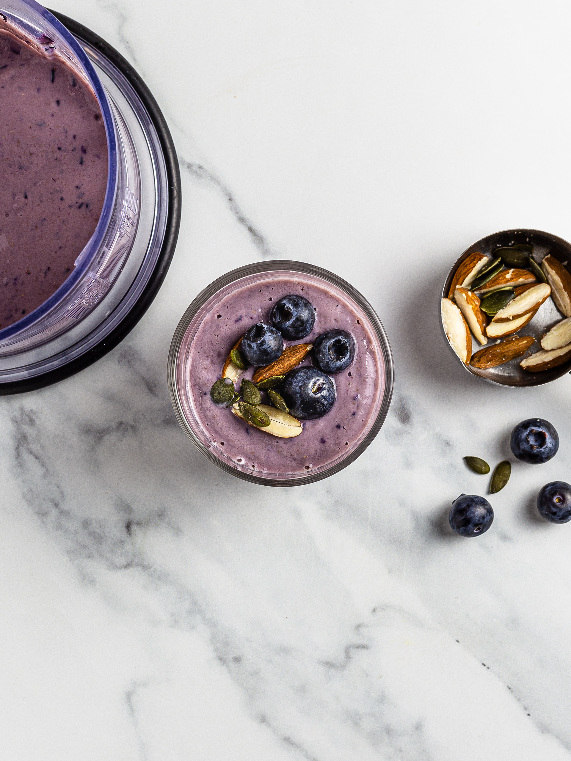 Blueberry smoothie topped with almonds and pumpkin seeds