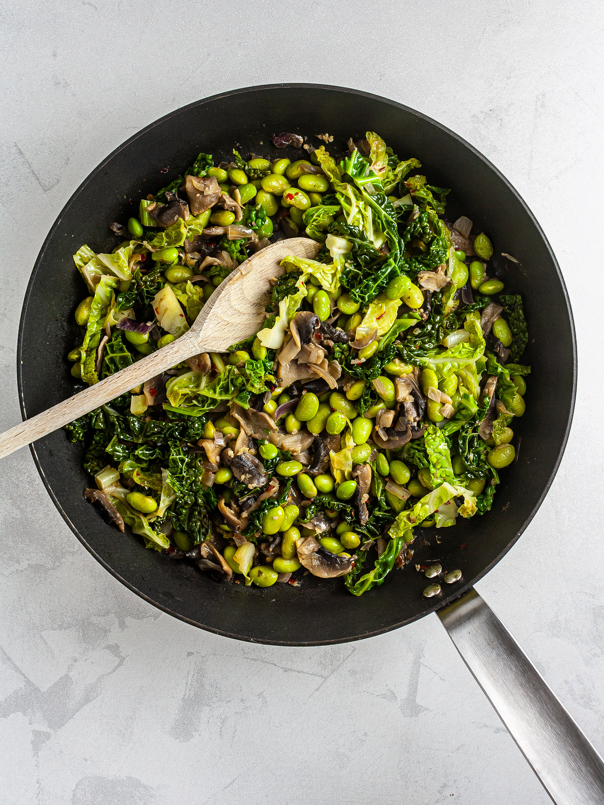 Cooked cabbage, mushroom, and edamame in a skillet