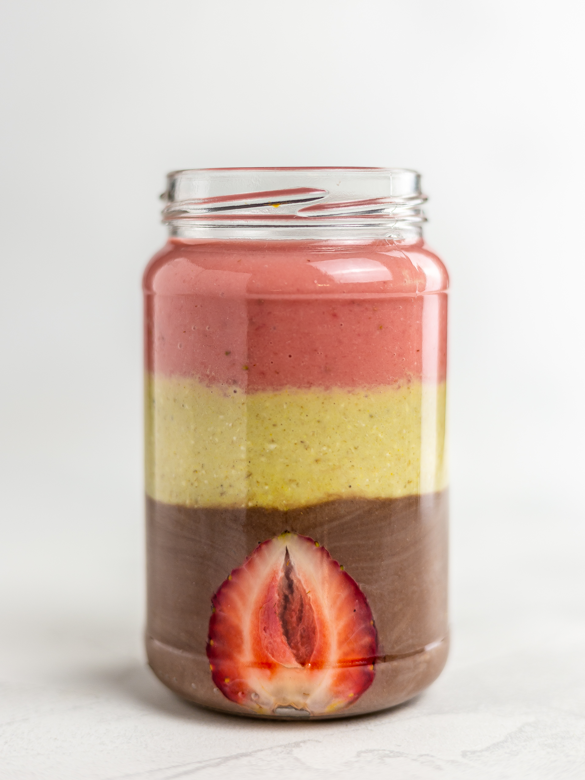 strawberry banana and chocolate layered smoothie in a bowl