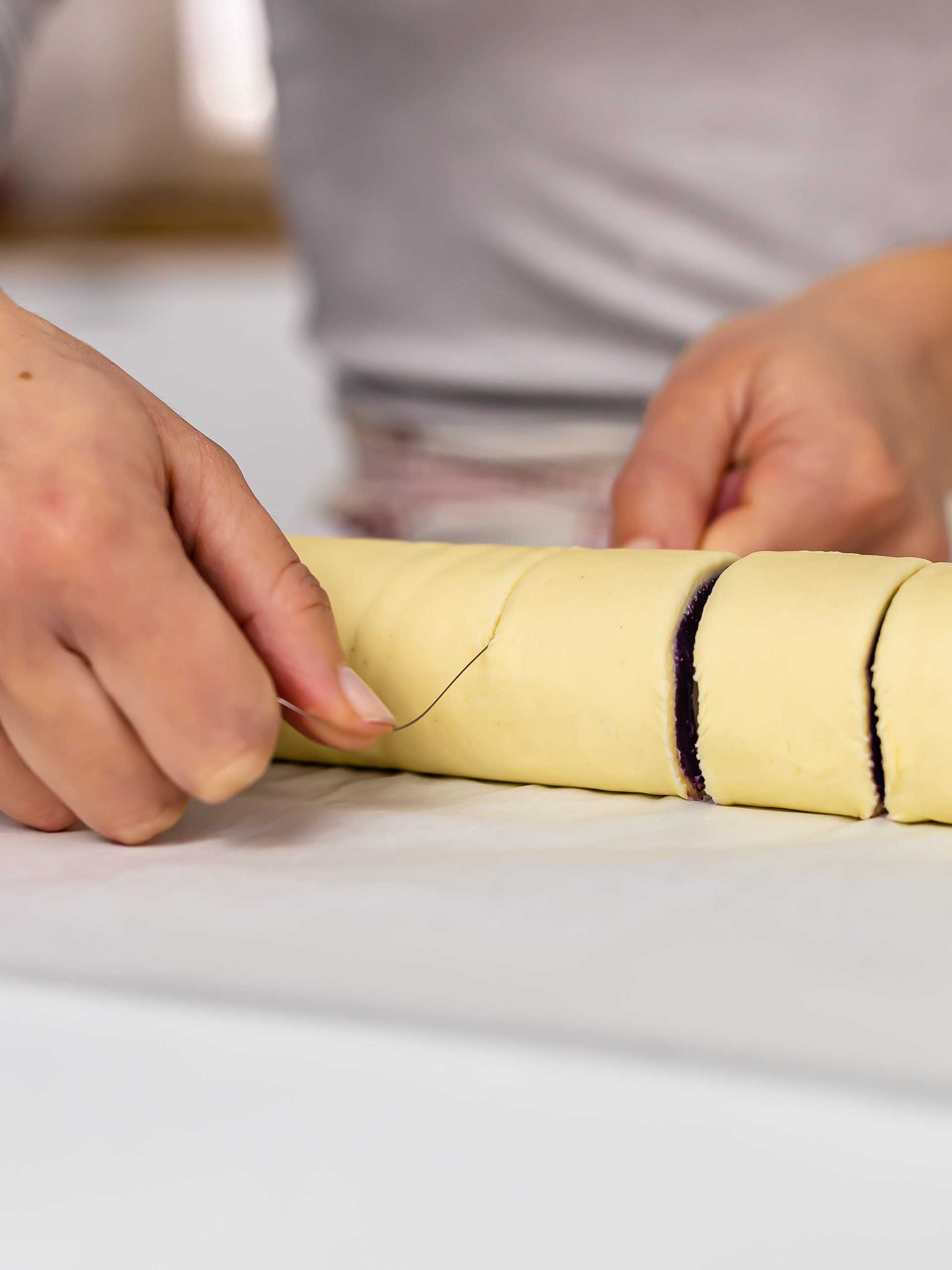 woman slicing pastry log into slices with a cake wire for cinnamon rolls