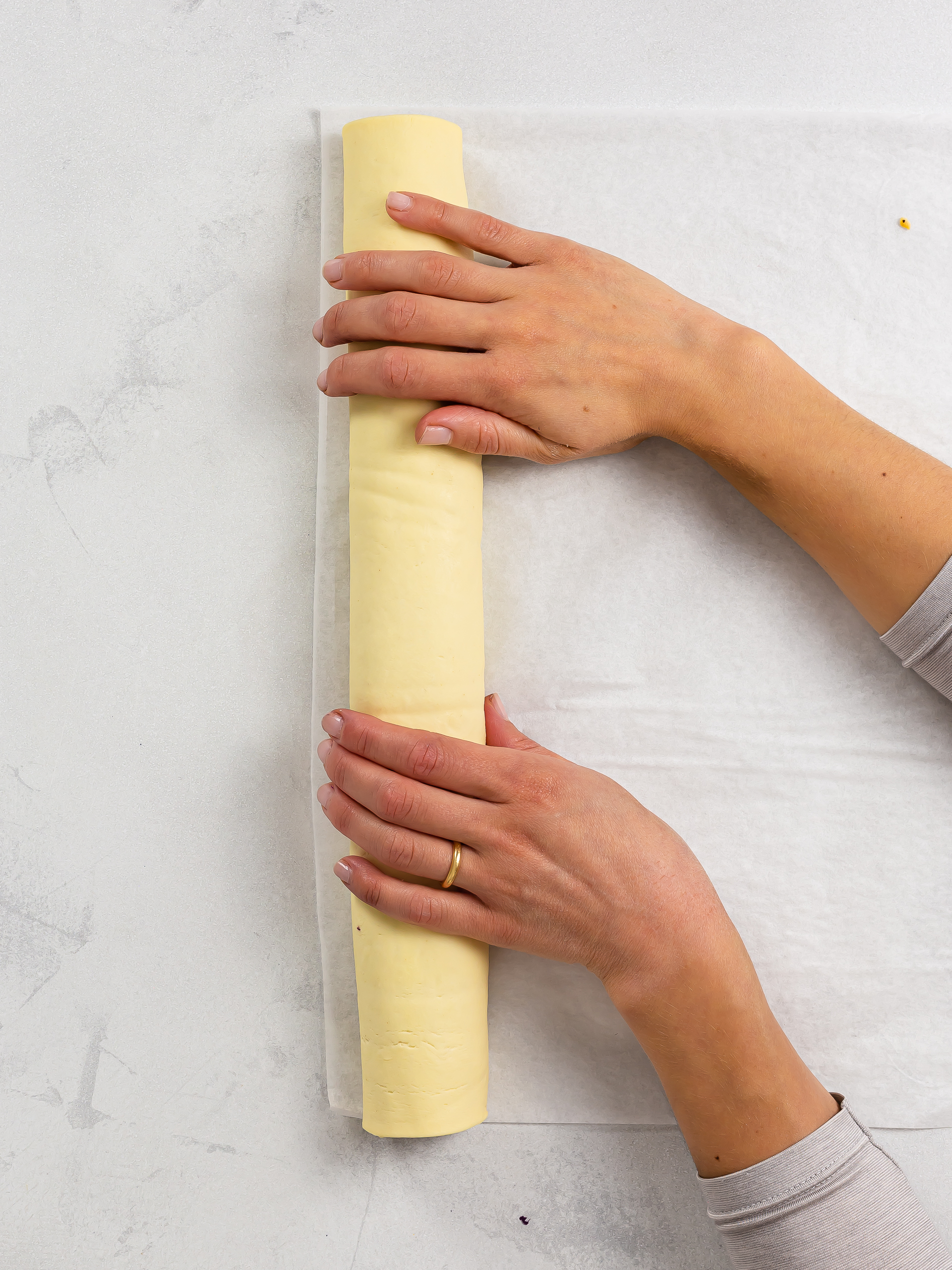 woman rolling pastry into a long log for cinnamon rolls