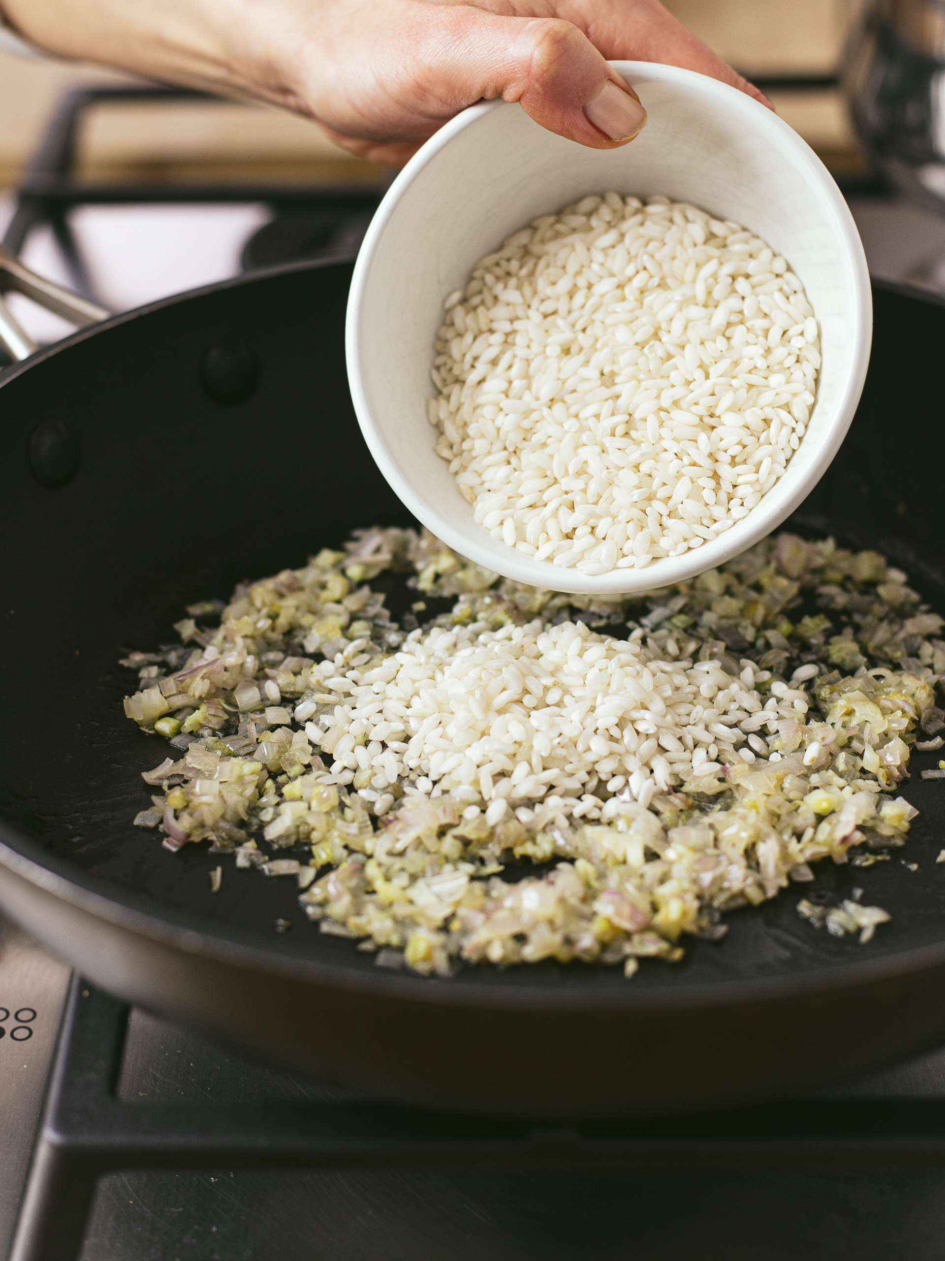 risotto rice added to cooked onions in a skillet