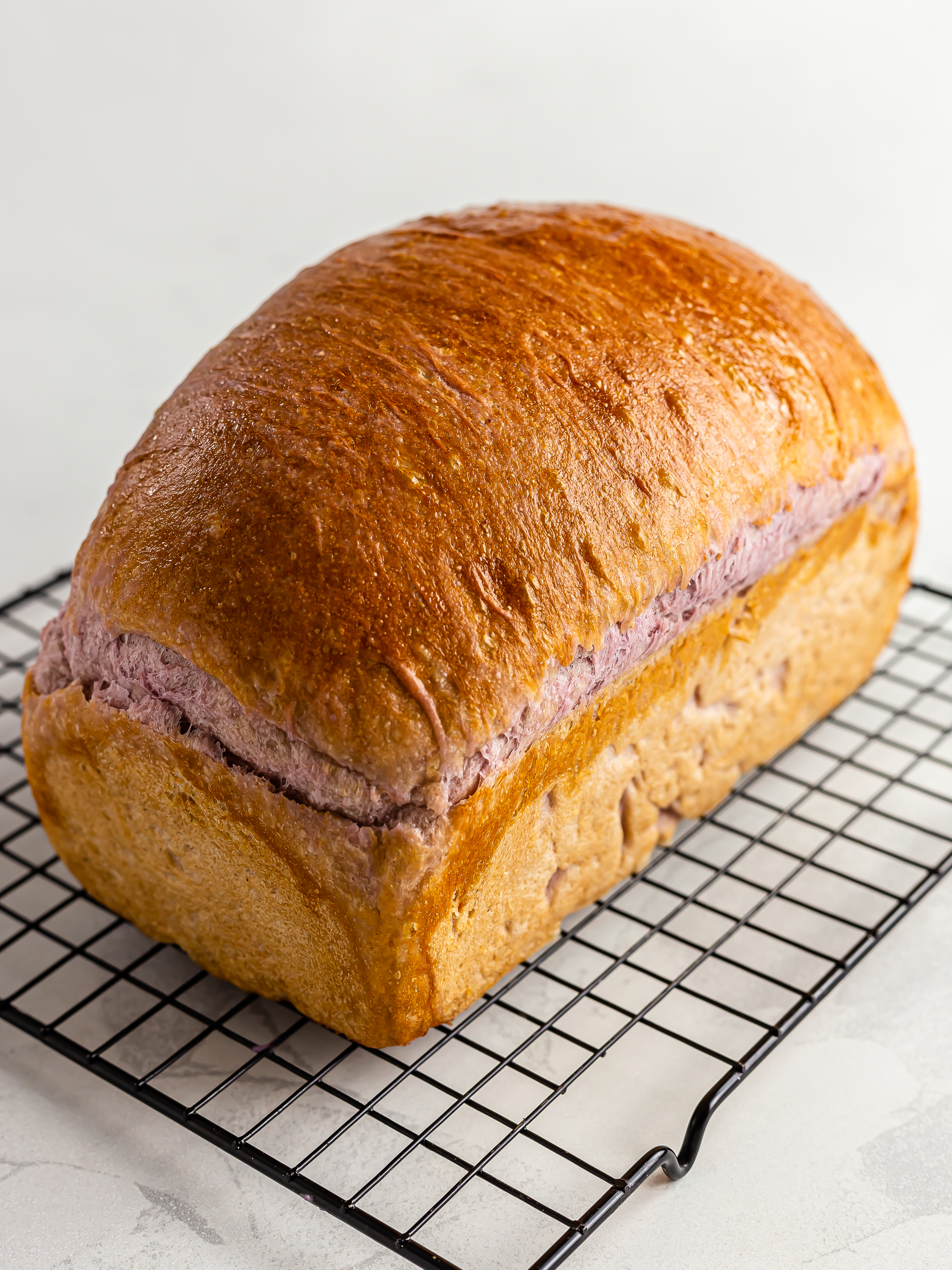 baked ube bread loaf cooling on a rack