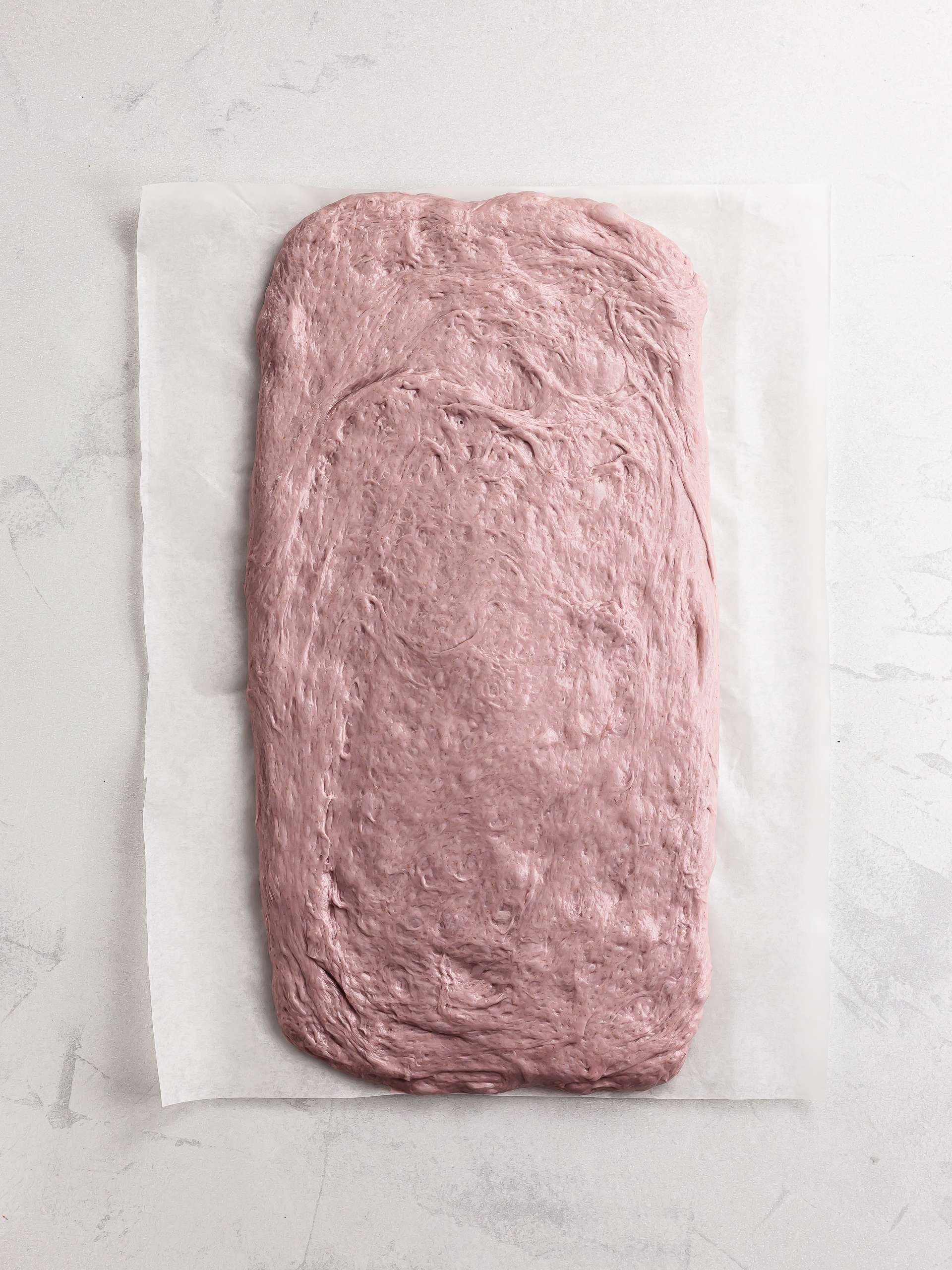 ube bread dough rolled out on baking paper