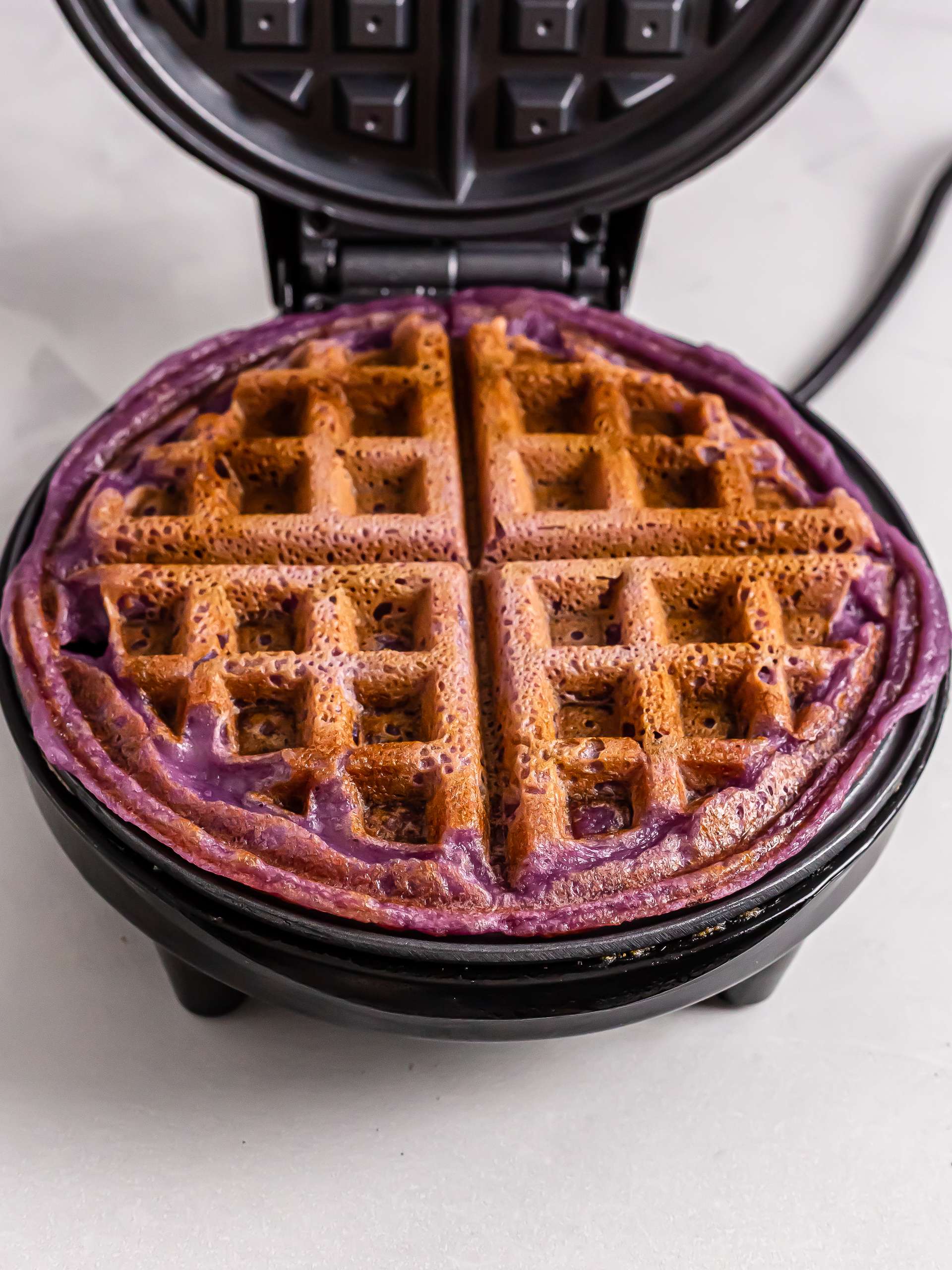 cooked ube mochi waffle in a waffle maker