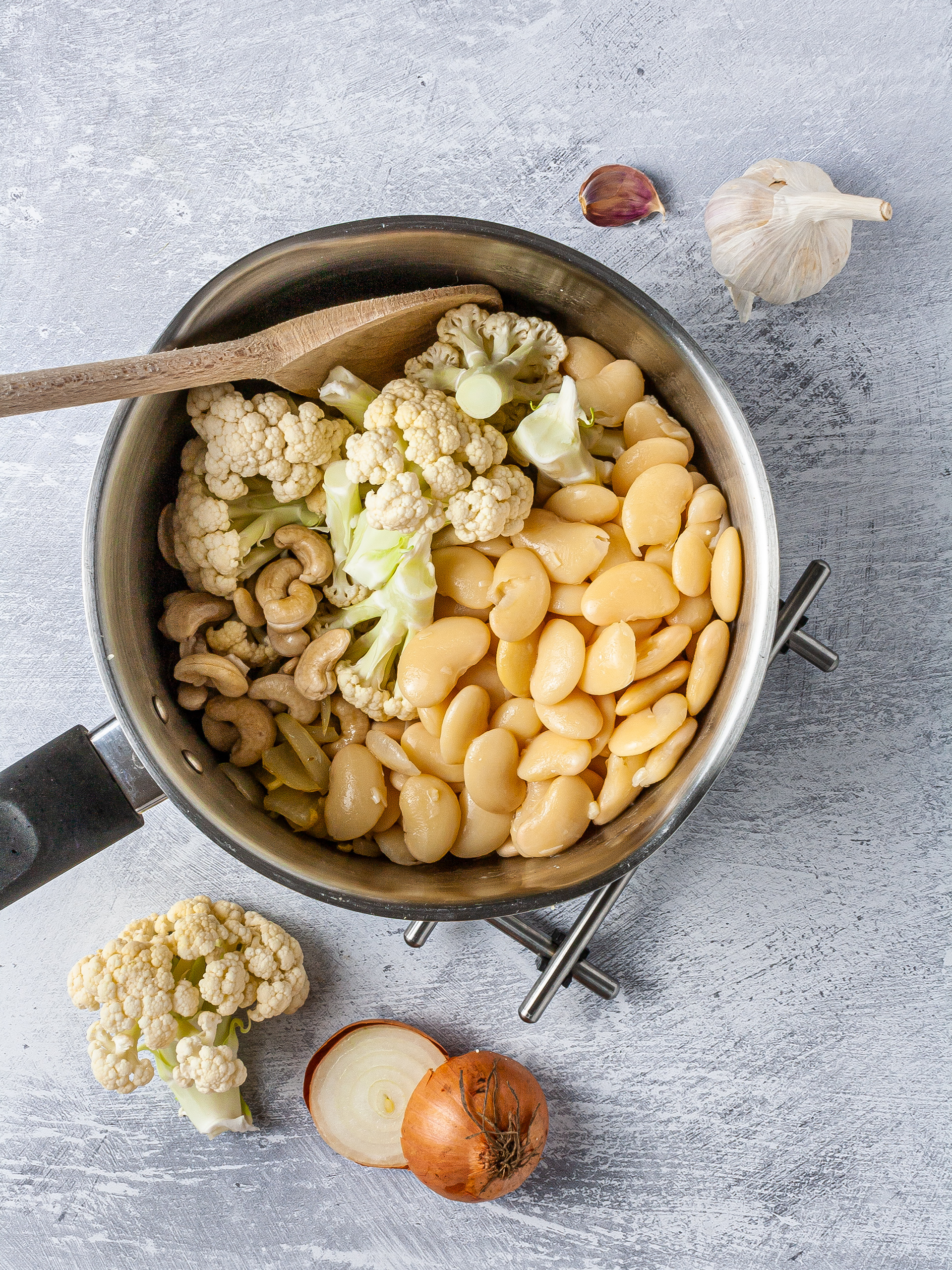 Onions, garlic, cauliflower, white beans in a pot