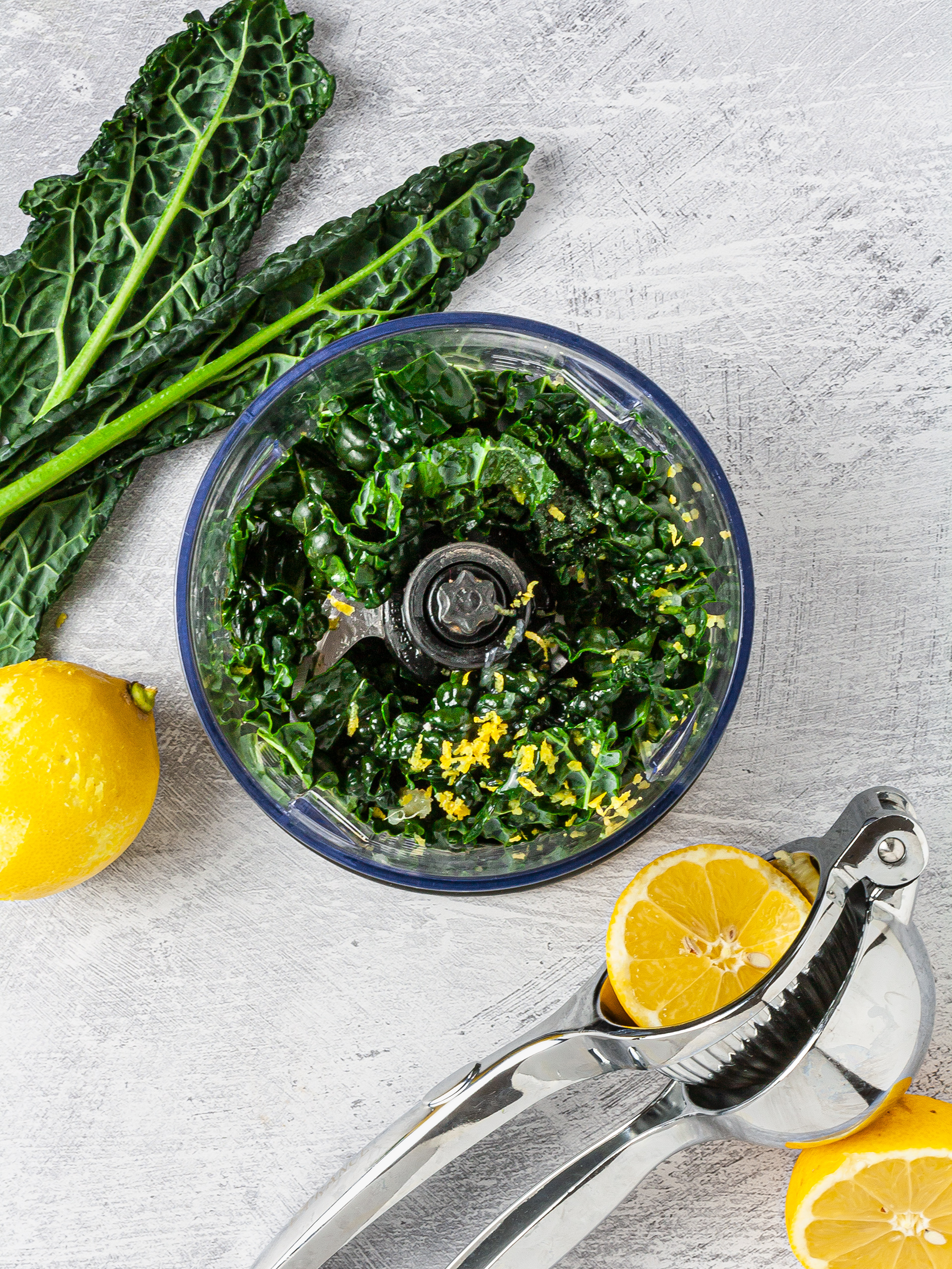 Kale pesto with lemon juice, lemon zest, and oil in a food processor