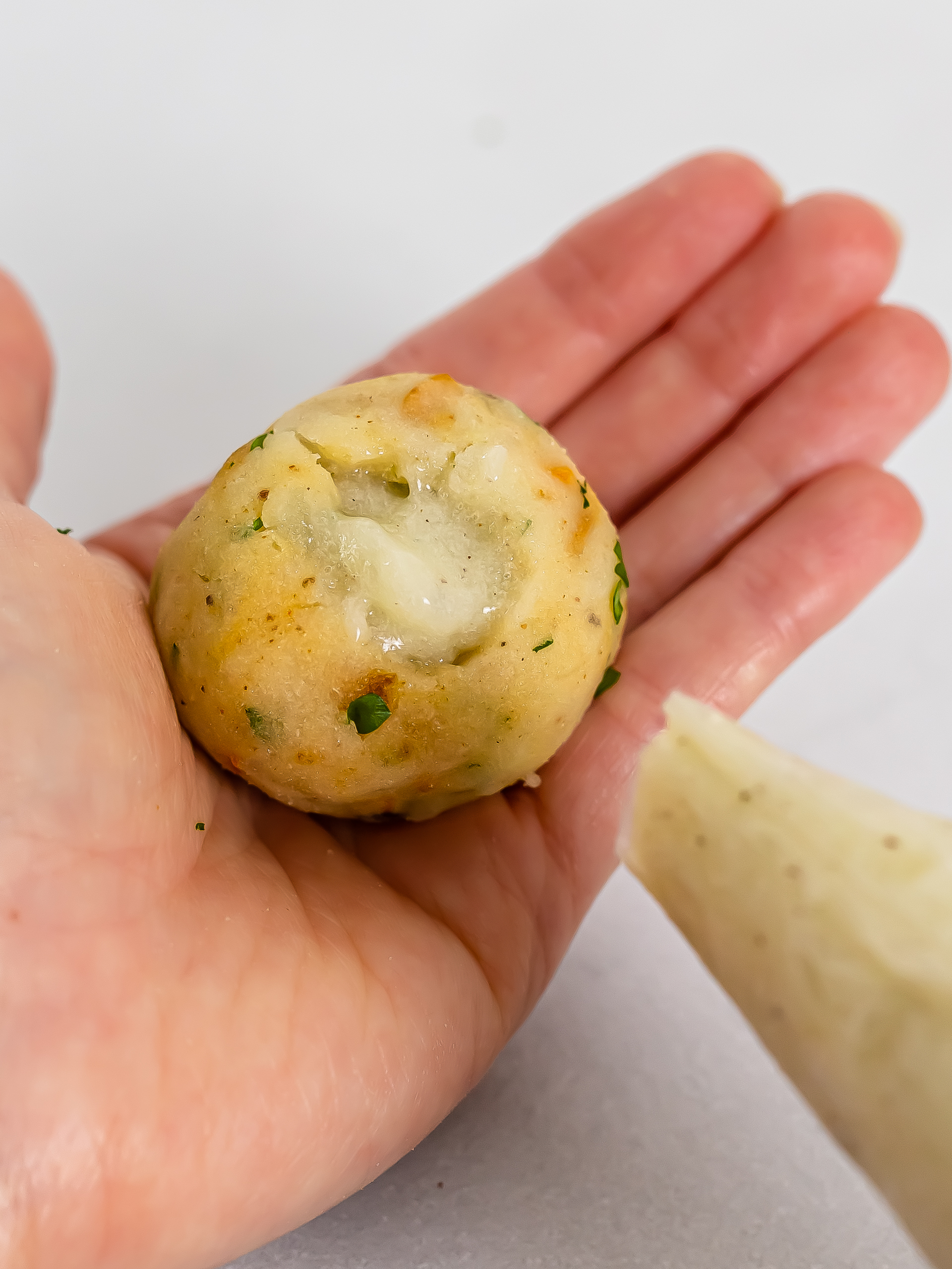 hand showing a croquette filled with potato cream