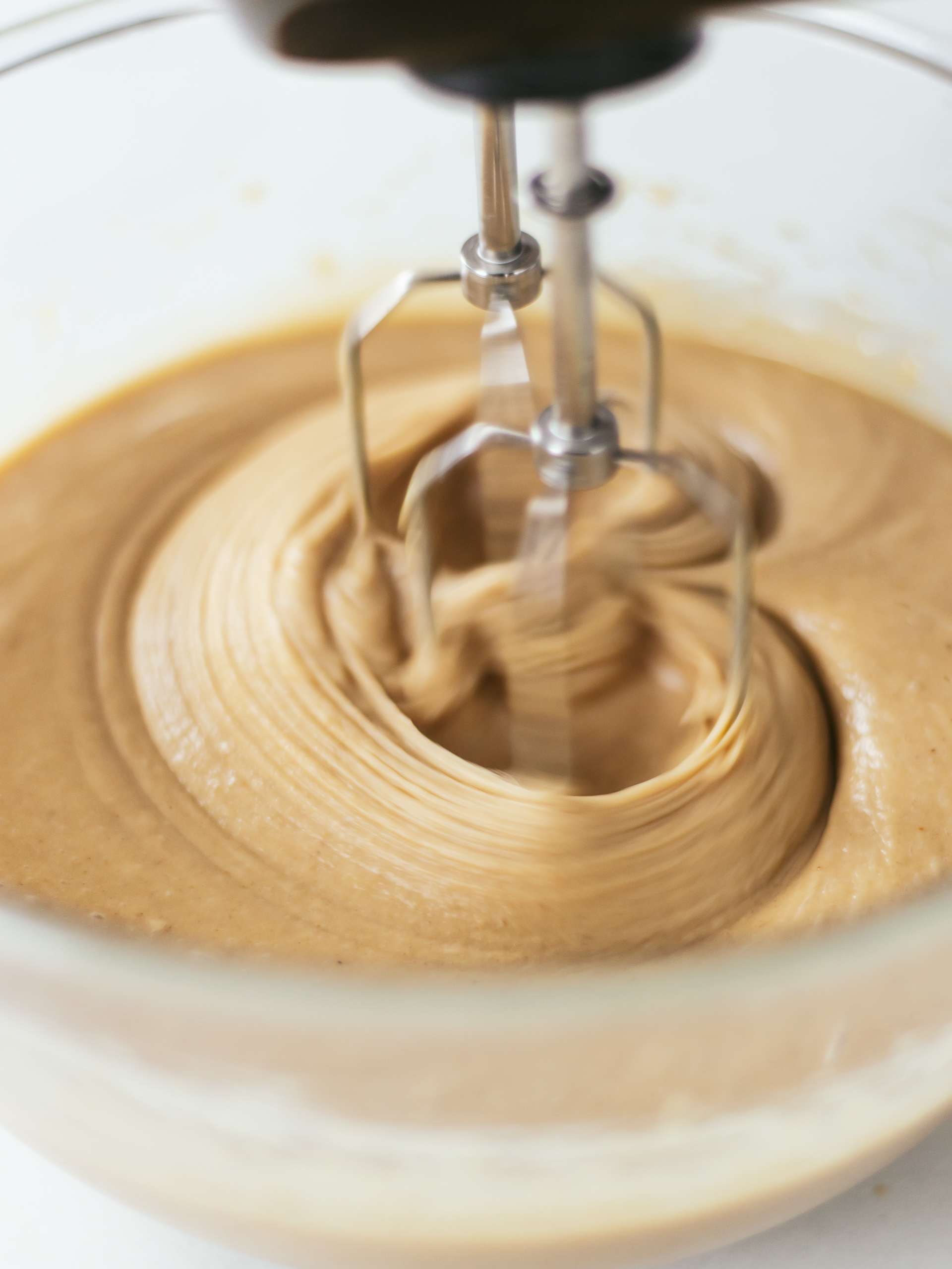 whisker mixing chai cake batter in a bowl