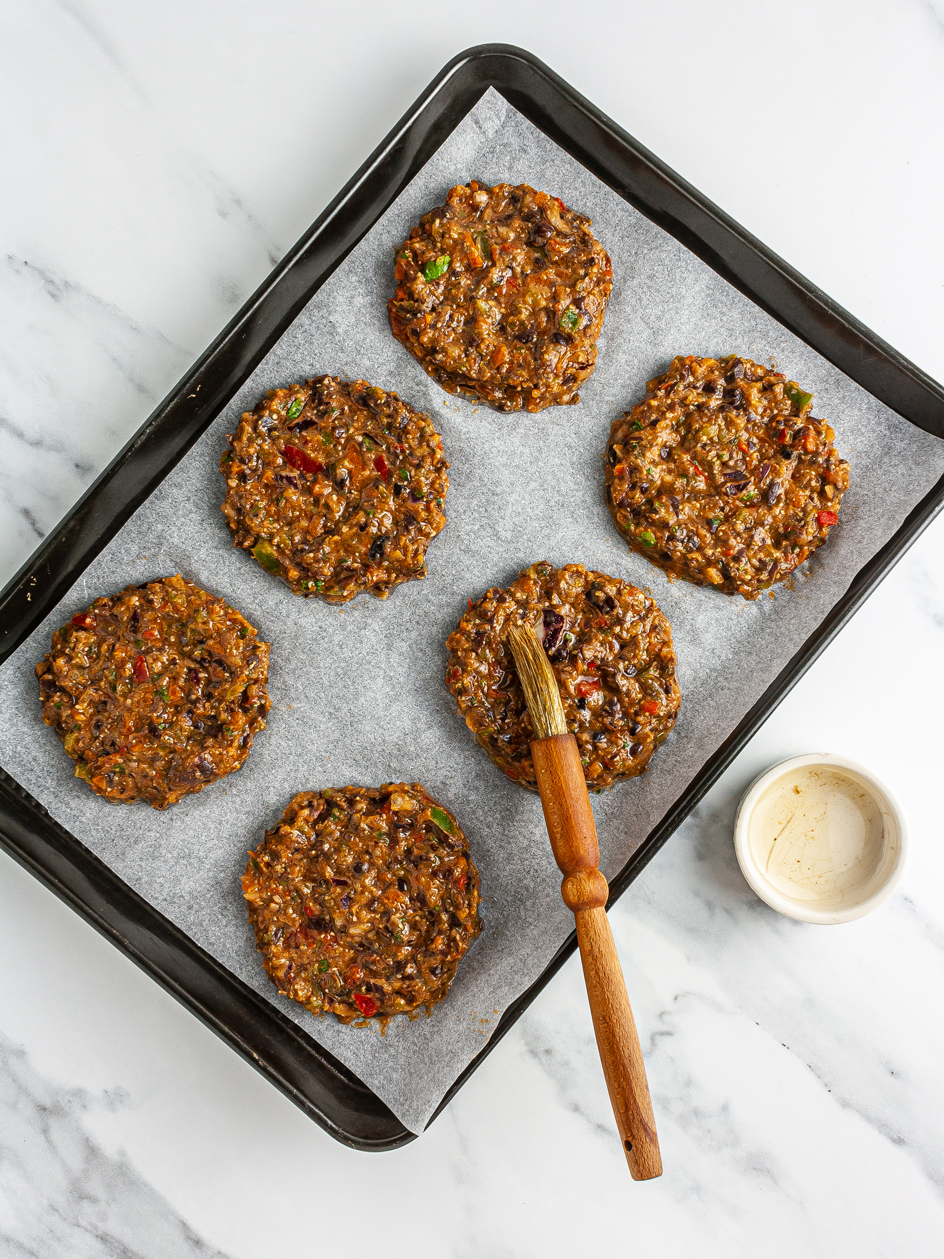 Shaped bean fritters on a baking tray brushed with oil