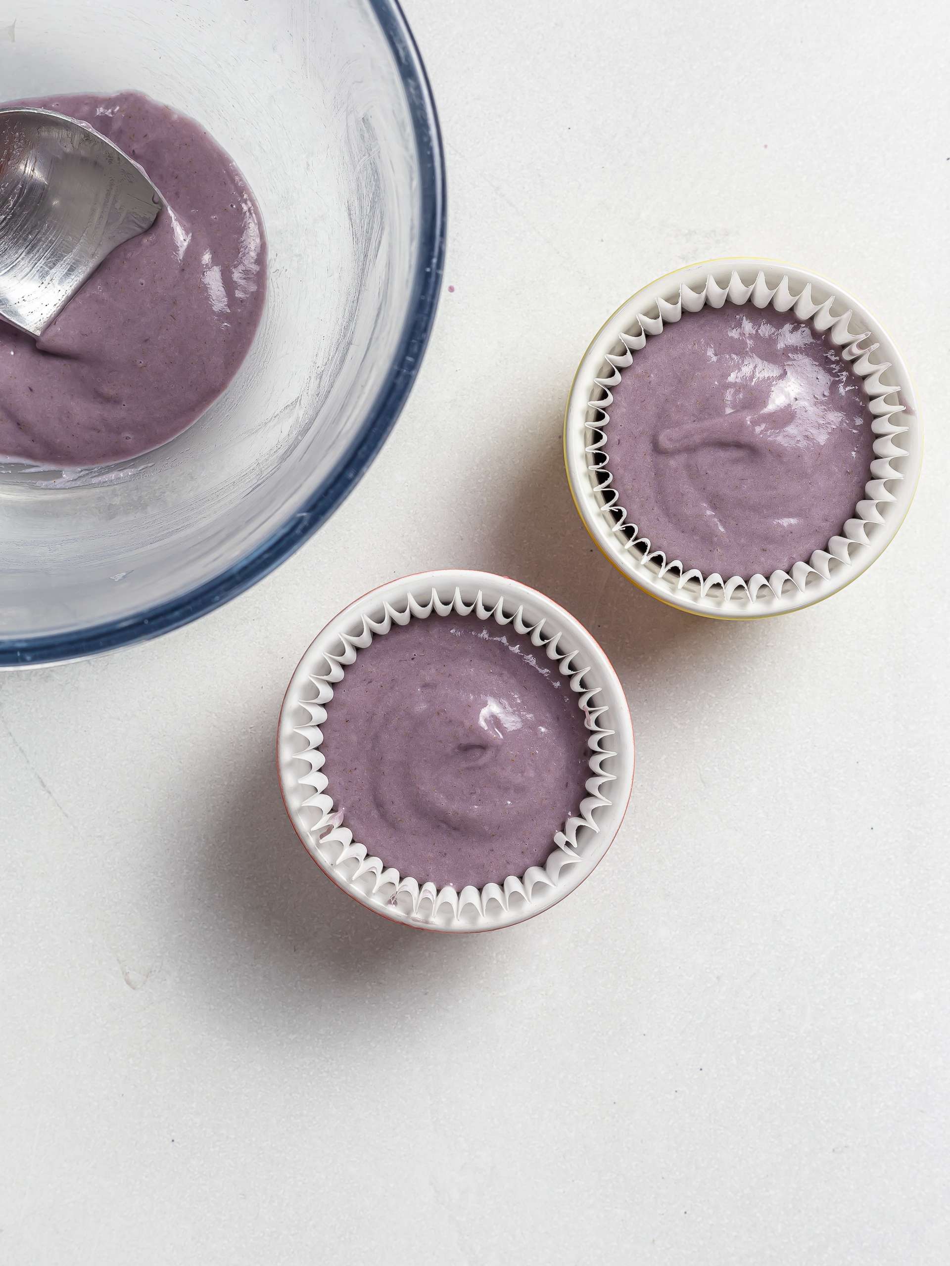 ube cupcake batter in ramekins with paper cases