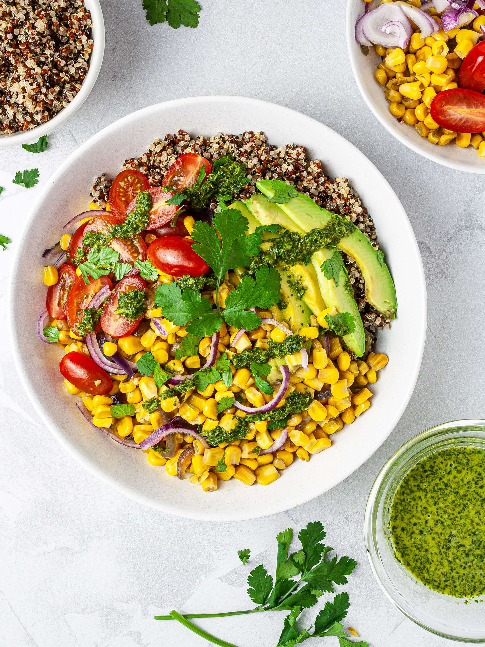 Corn, avocado, tomato, and quinoa salad in a serving bowl with fresh cilantro and lime dressing.