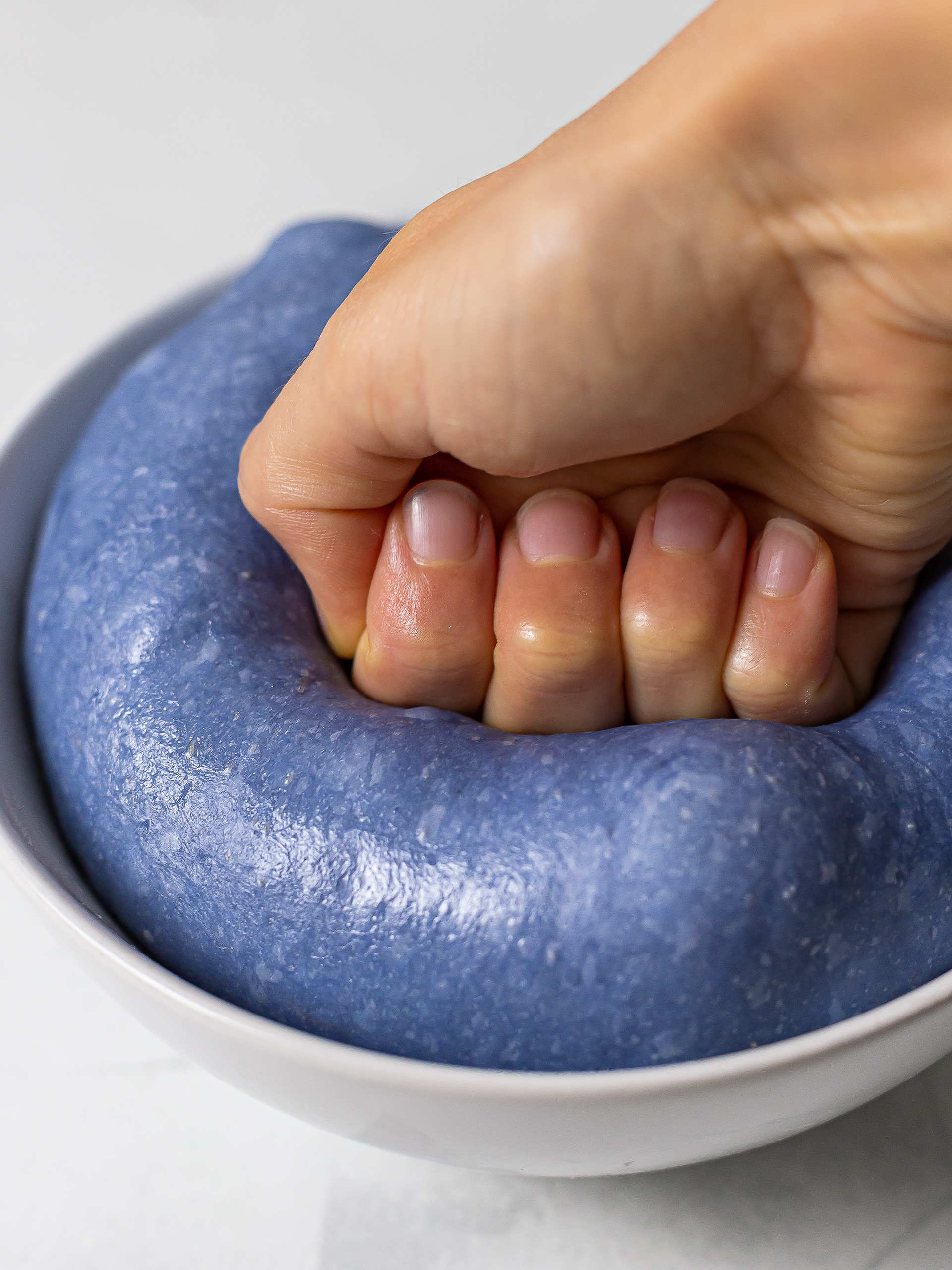 punching blue pea bread dough to remove excess air