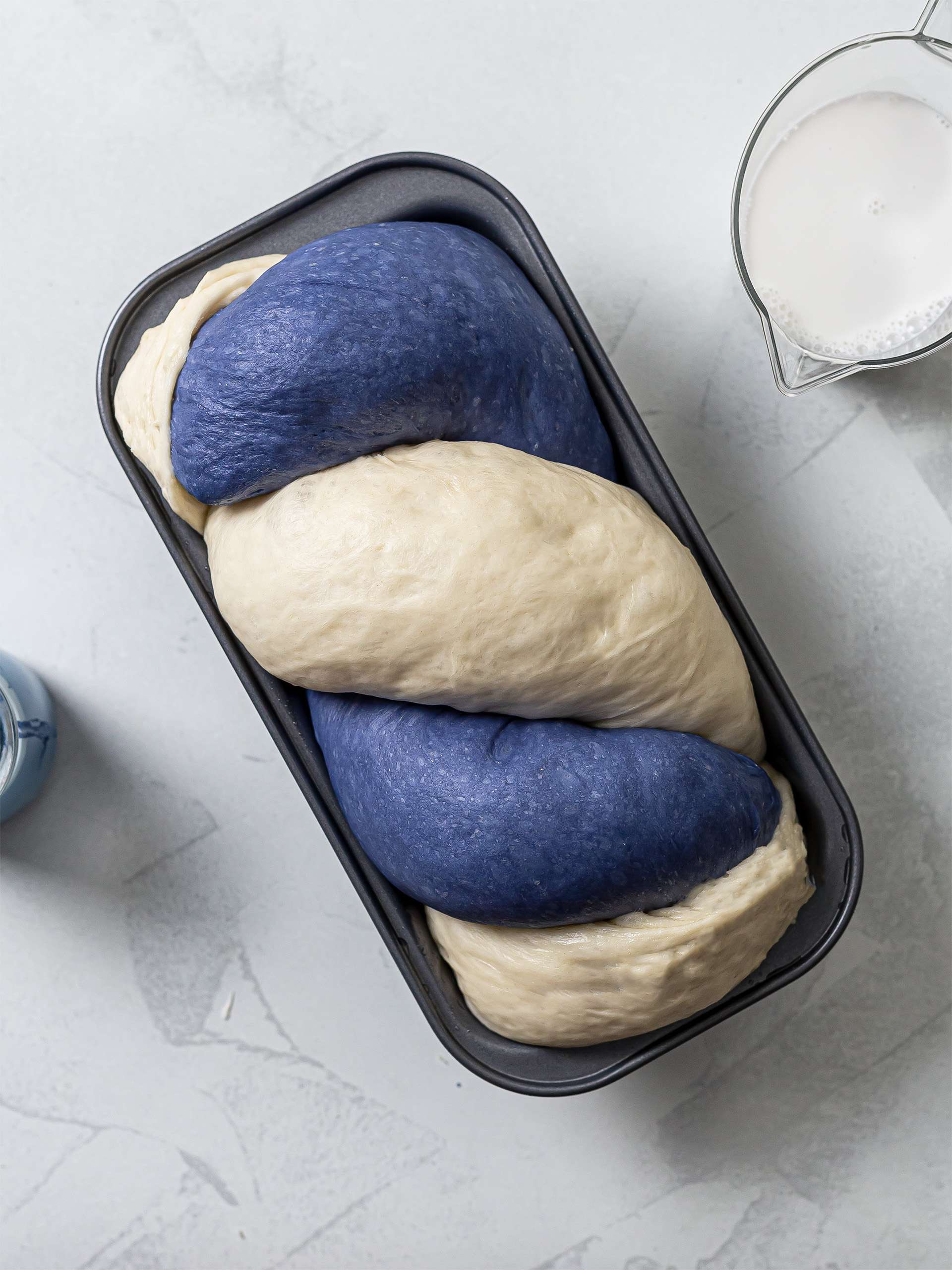 braided blue bread proving a loaf pan