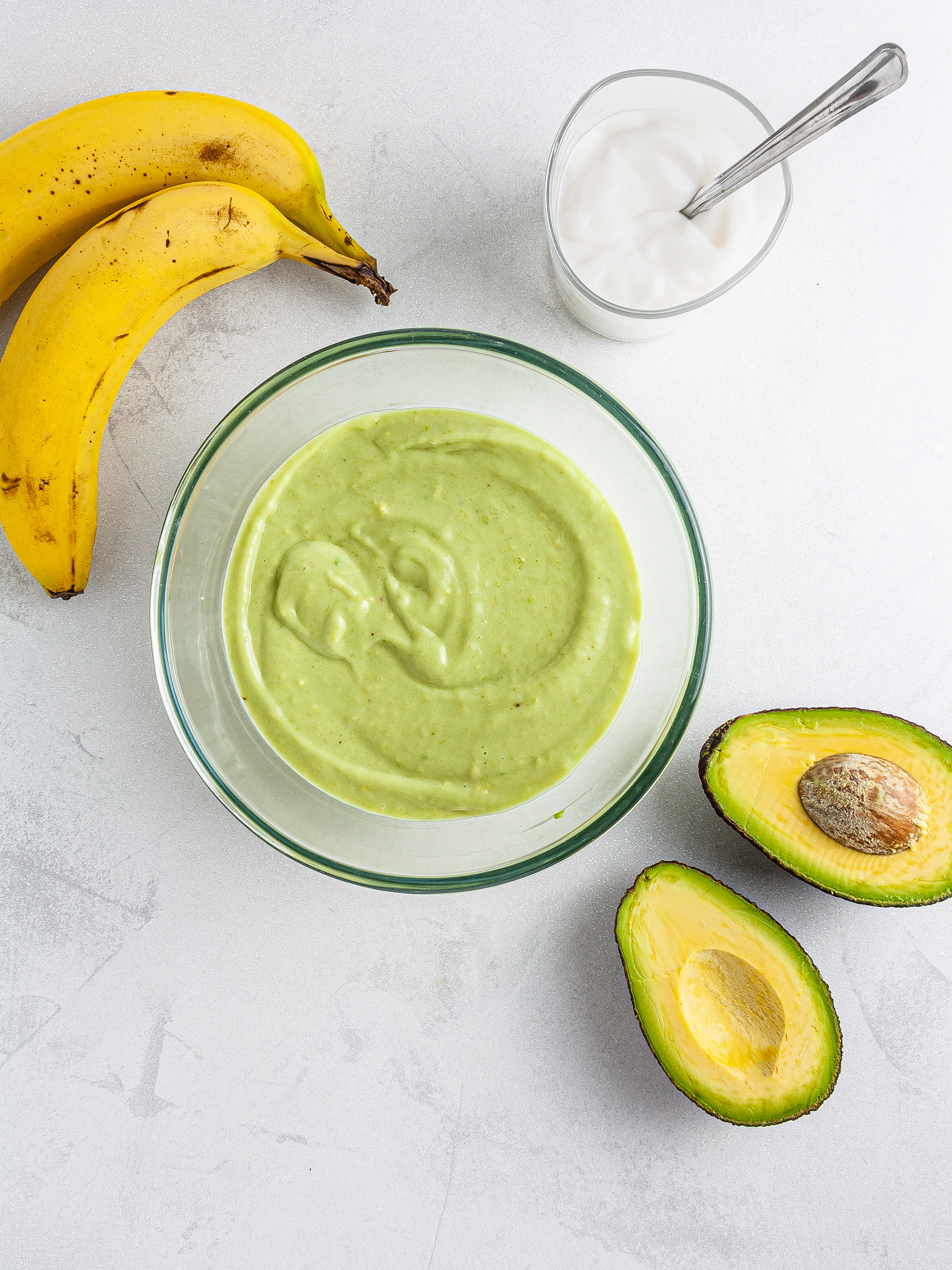 Blended avocados, bananas, and yogurt in a mixing bowl