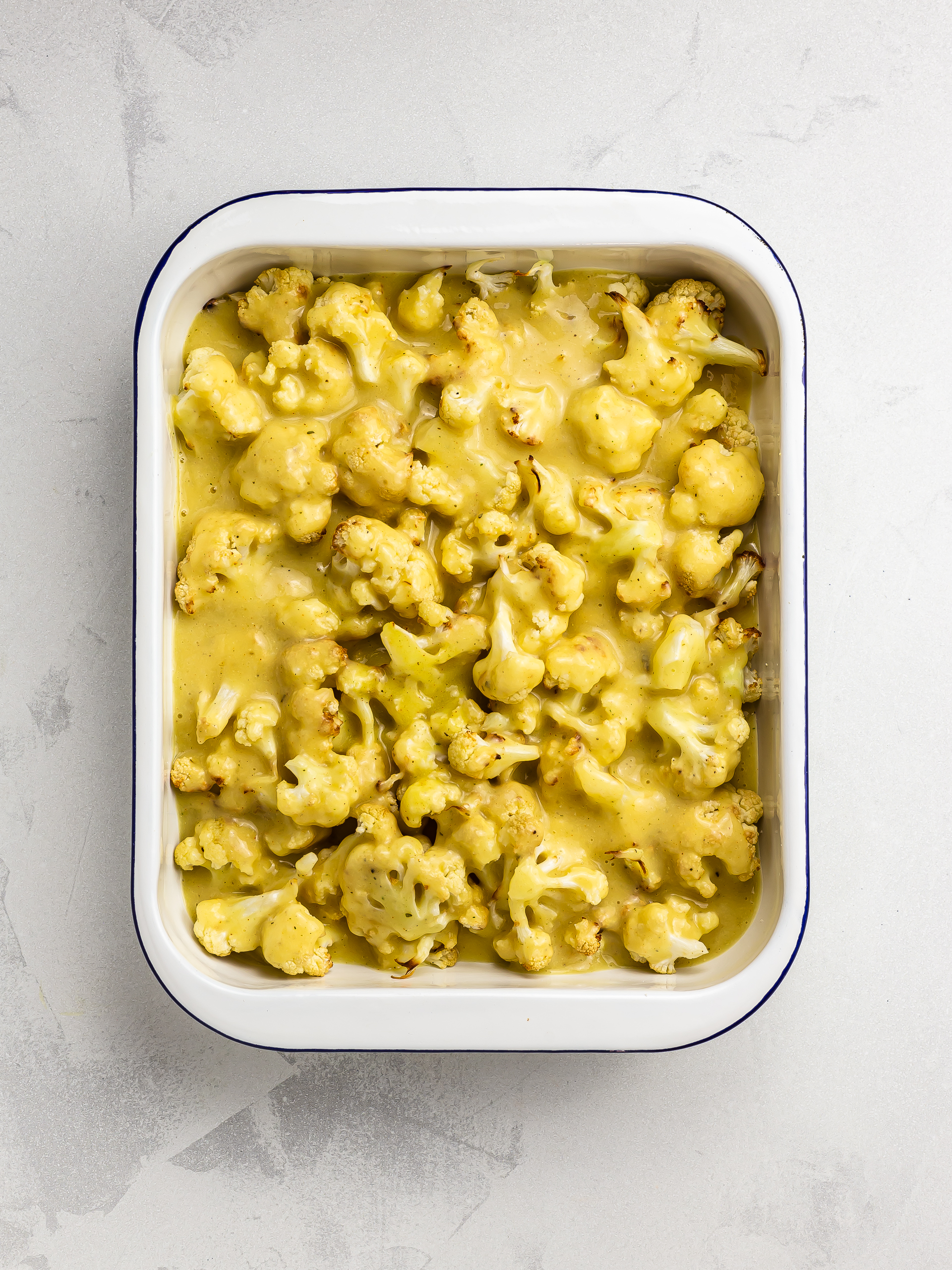 cauliflowers in a baking dish with white sauce