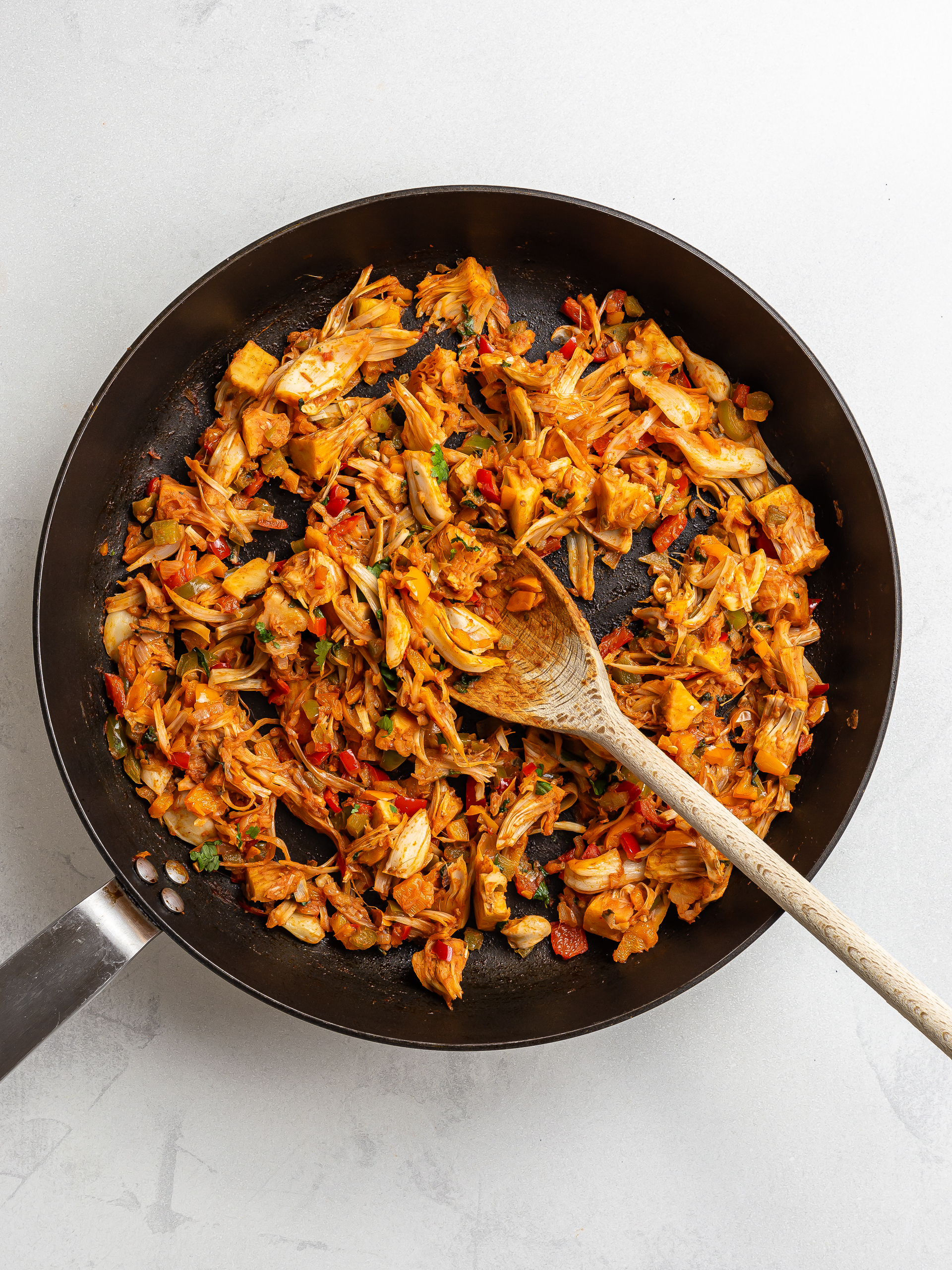 jackfruit and peppers cooked with enchilada sauce in a skillet
