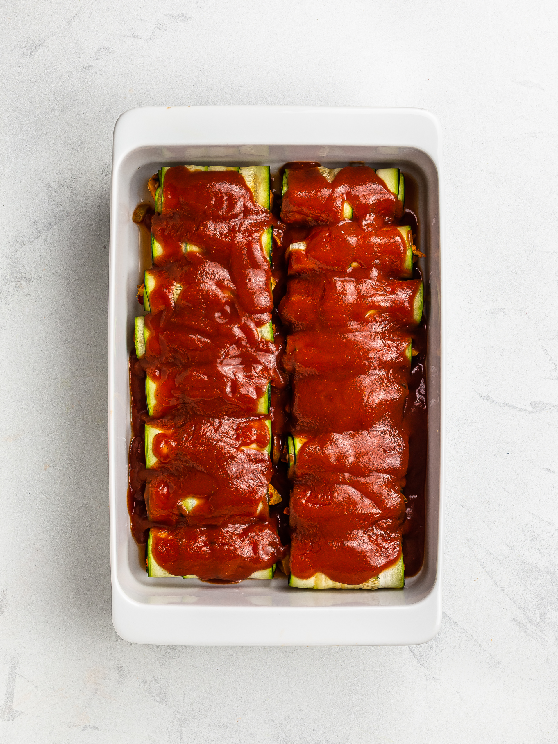 zucchini enchiladas in a casserole dish topped with tomato sauce