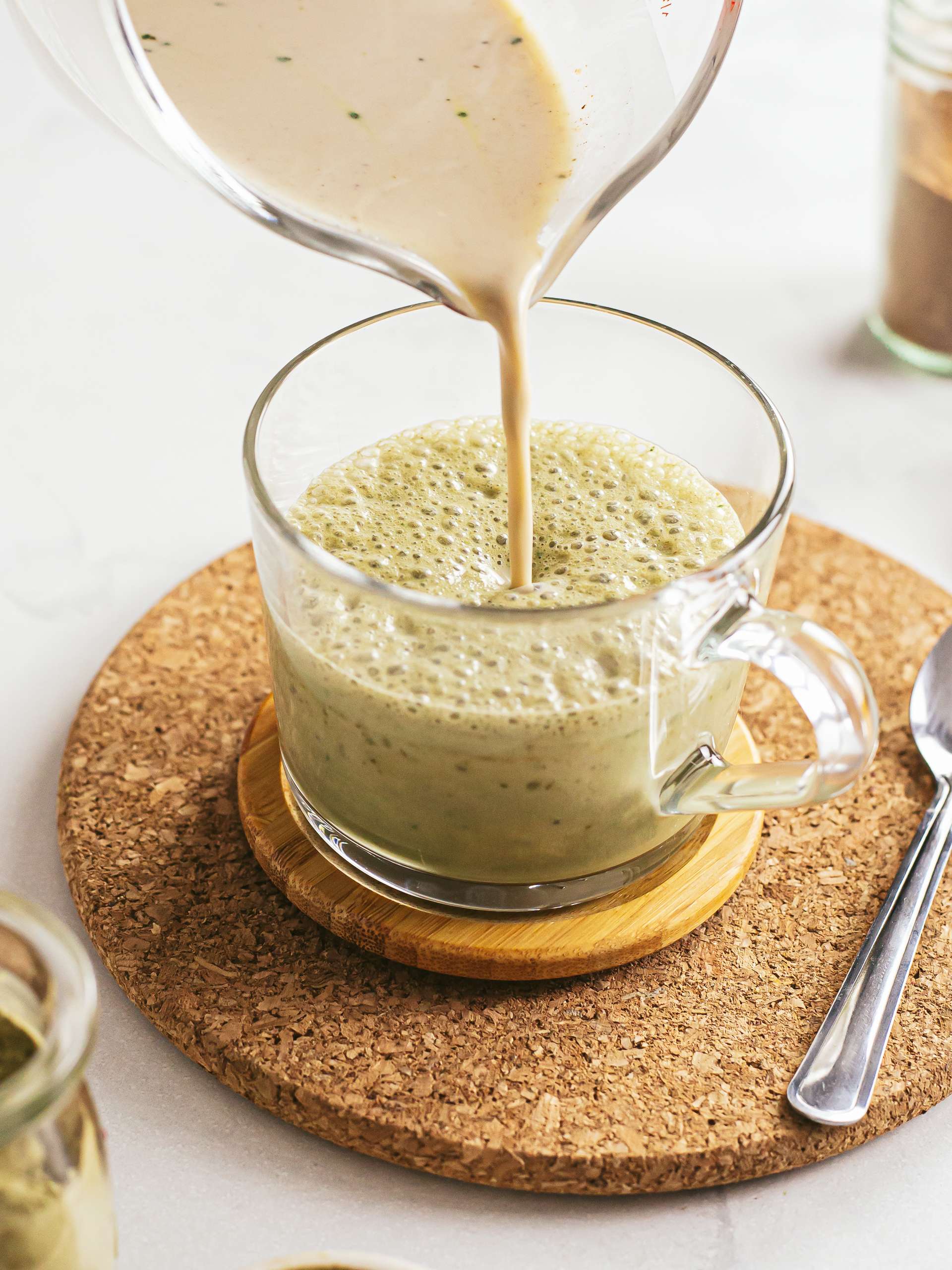 pouring chai spiced latte into matcha latte