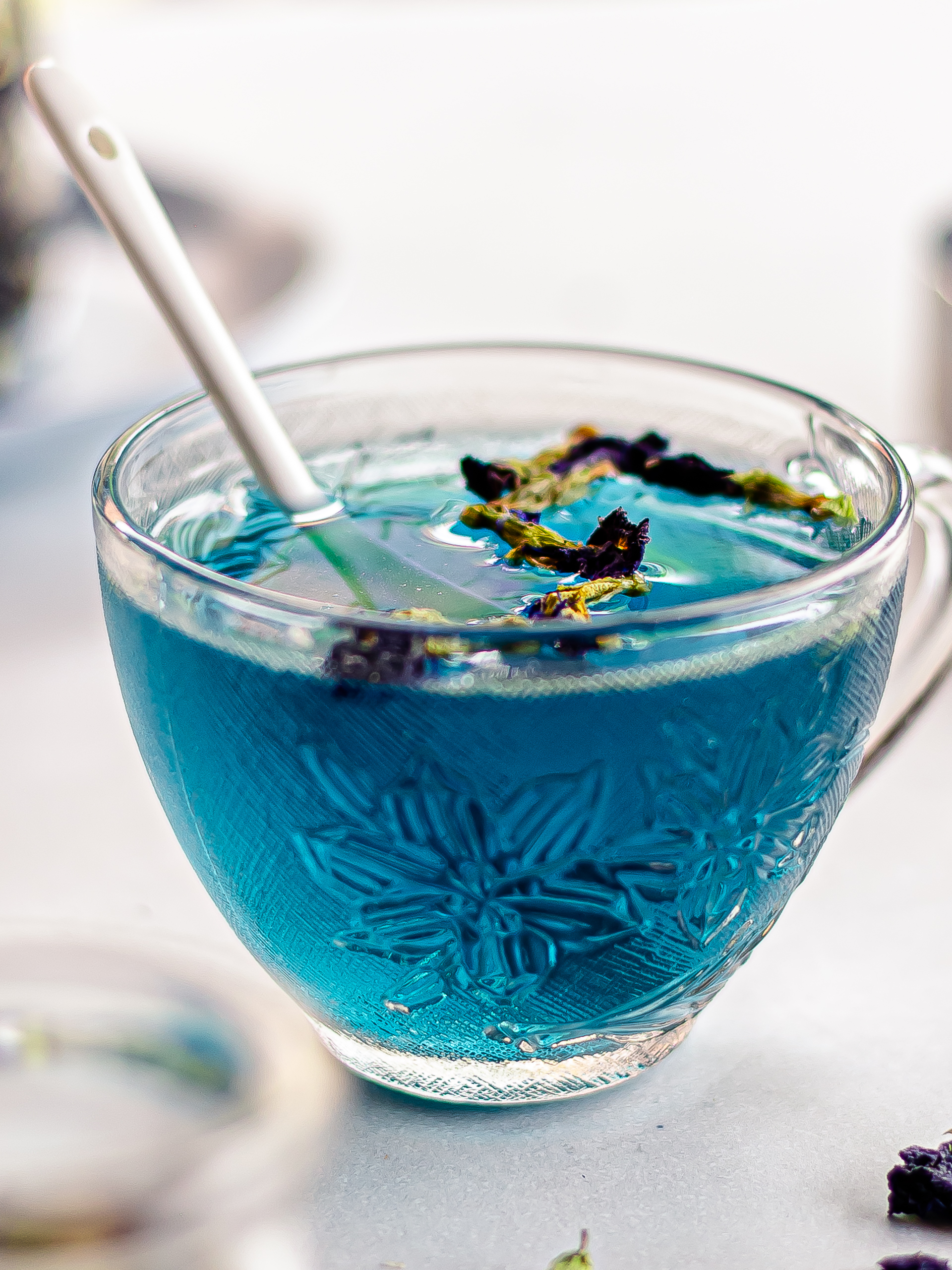 blue butterfly pea tea in a cup with dried flowers