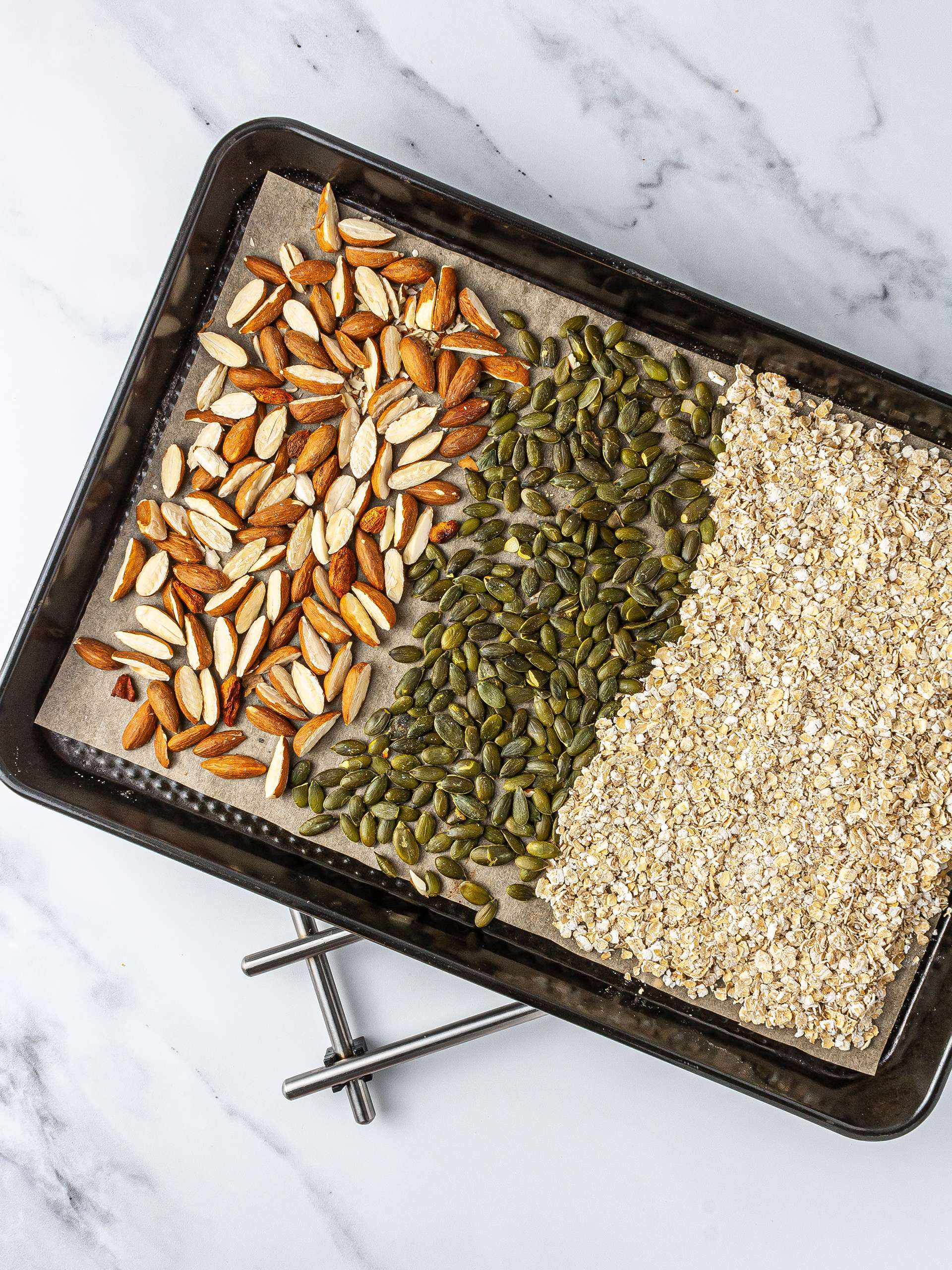 Oat flakes, almonds, and pumpkin seeds roasted in a baking tin.