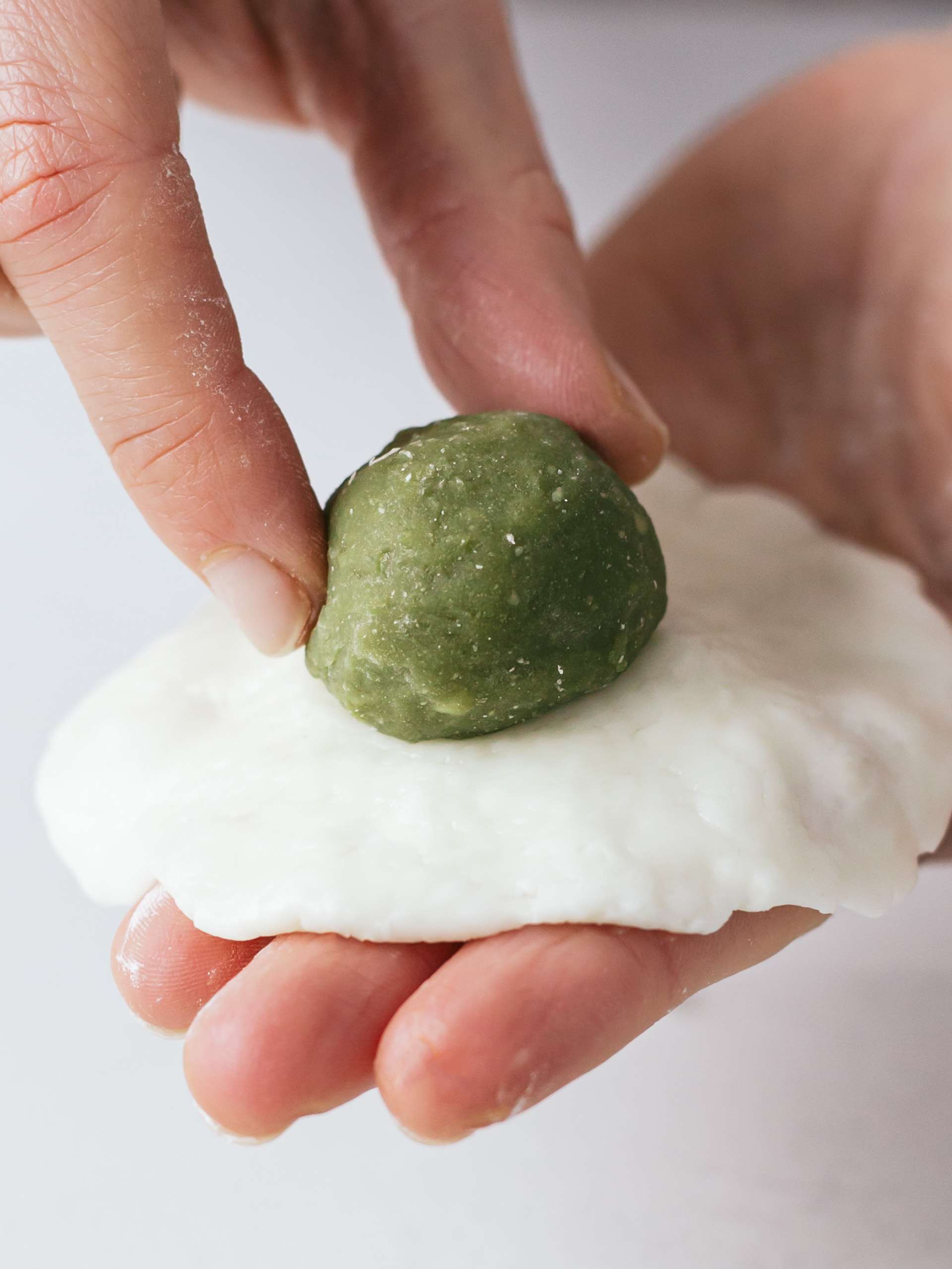 matcha mochi ball placed onto a dish of cookie dough