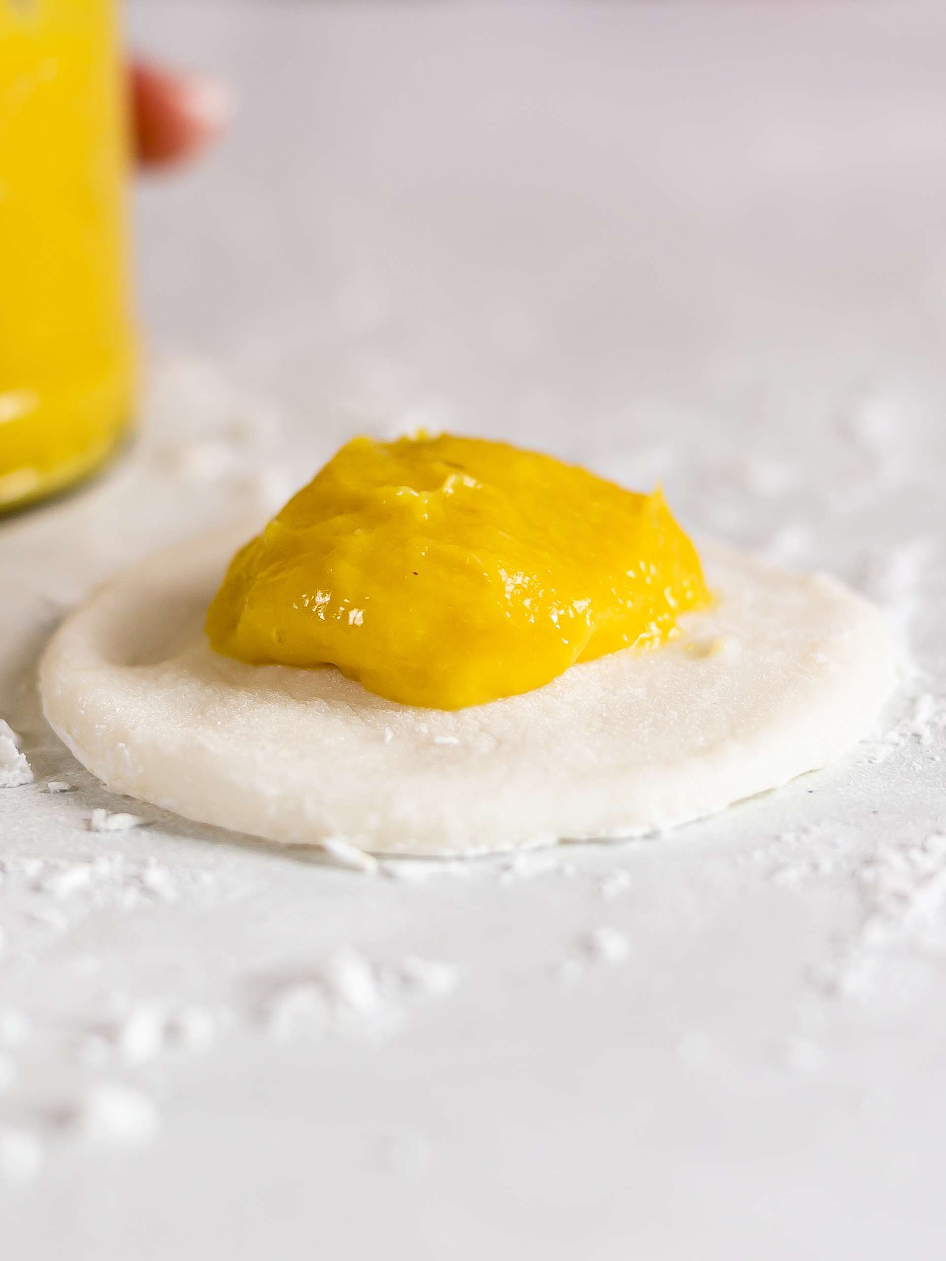 mochi dough wrapper with a spoon of mango jam in the centre