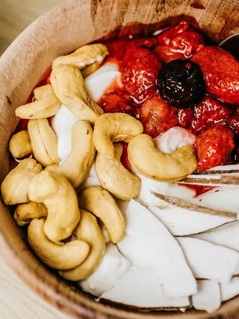 cashew nuts in a bowl with berries and coconut